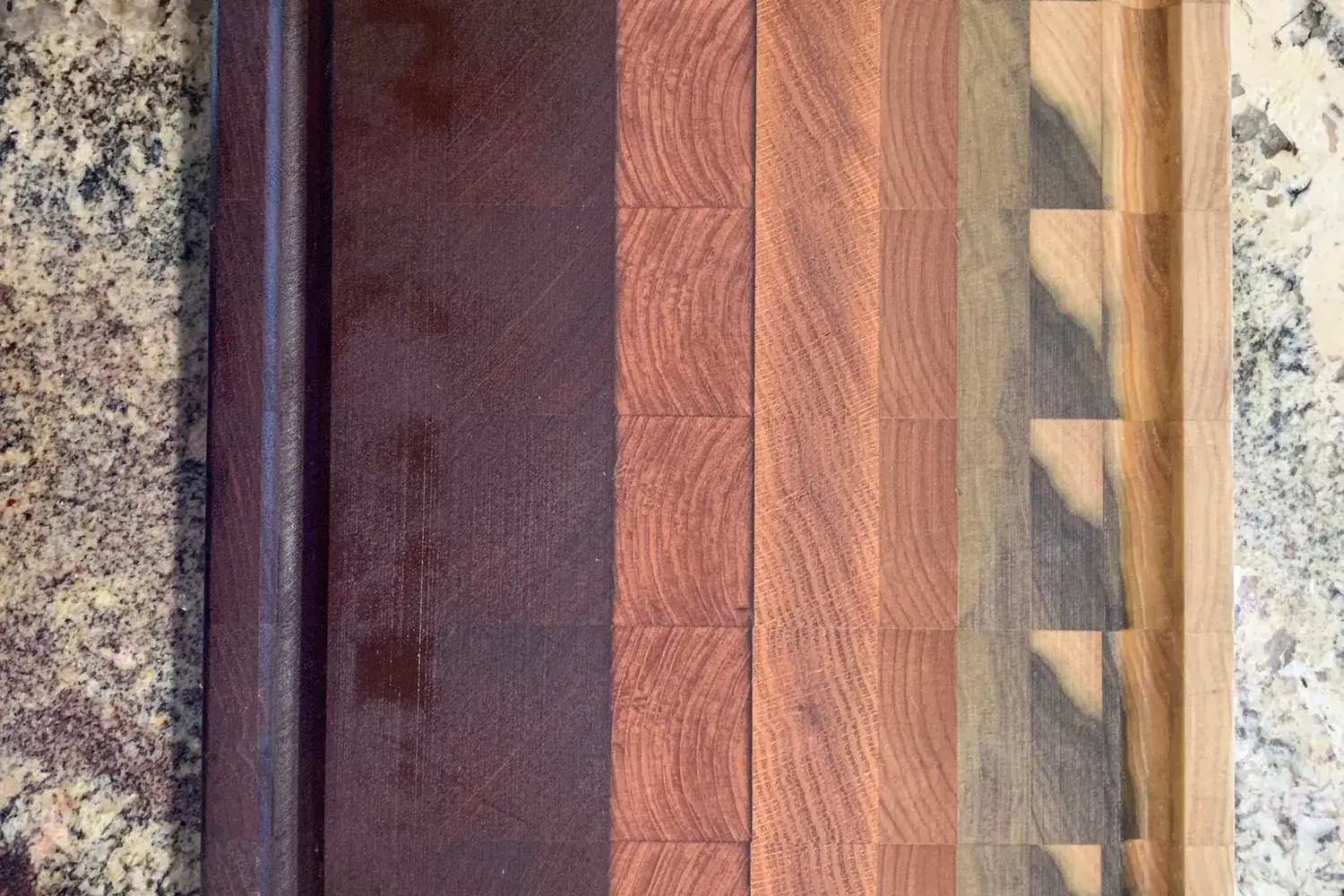 A striped hardwood cutting board made of alternating light and dark wood strips