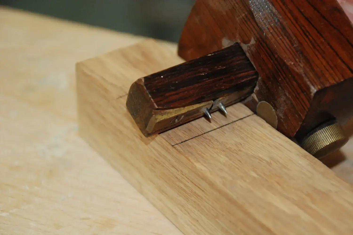 A wooden mortise gauge scribing parallel lines on the face of a board