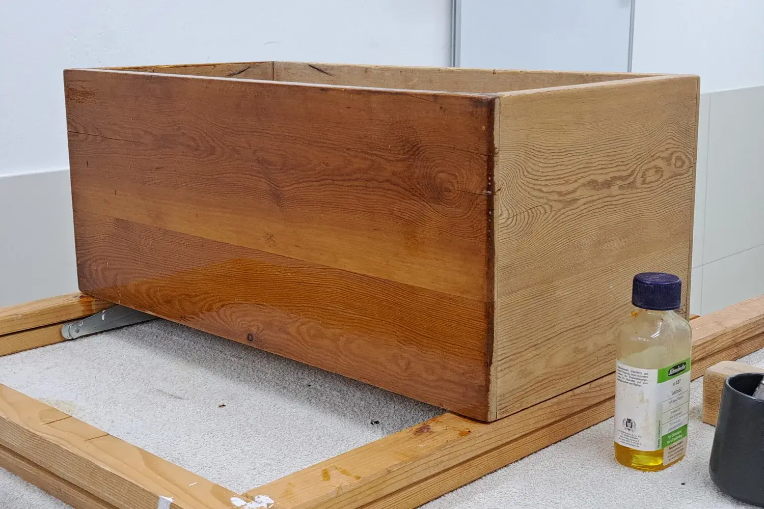 A simple pine box glistening with a fresh coat of linseed oil, next to a bottle of oil